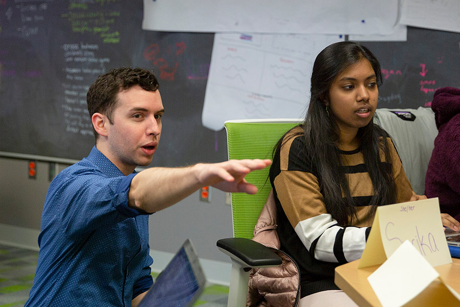A graduate student instructor explains a project to a student in class