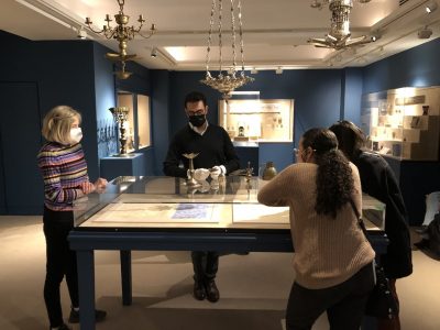 Students listening to a museum guide, standing around a table